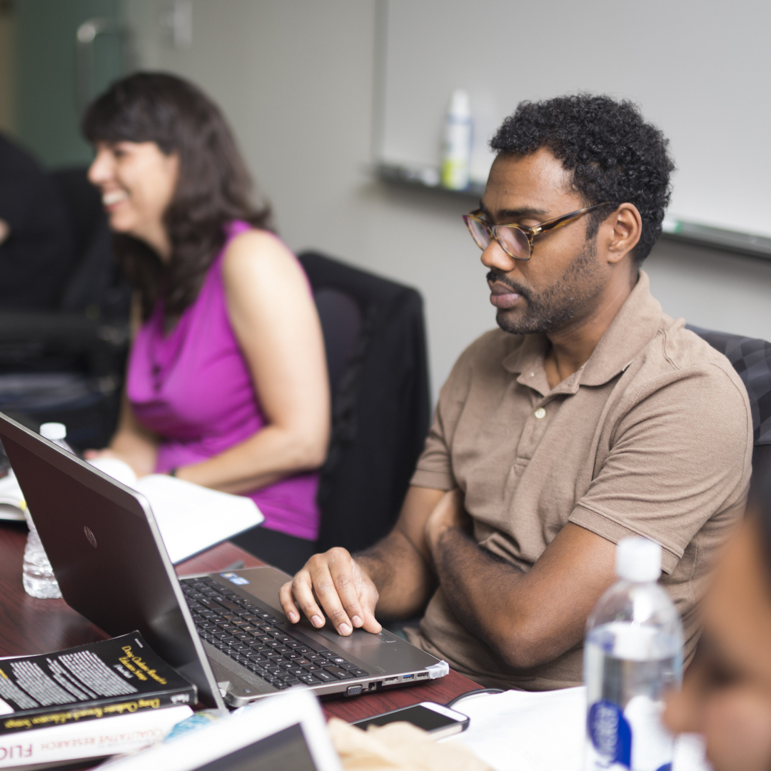 Two graduate students in classroom in front of laptops