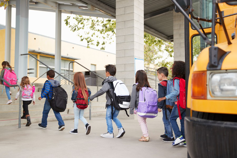 Photo of elementary students walking from school bus to building