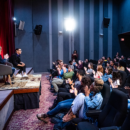 Group of students listening to speaker on stage
