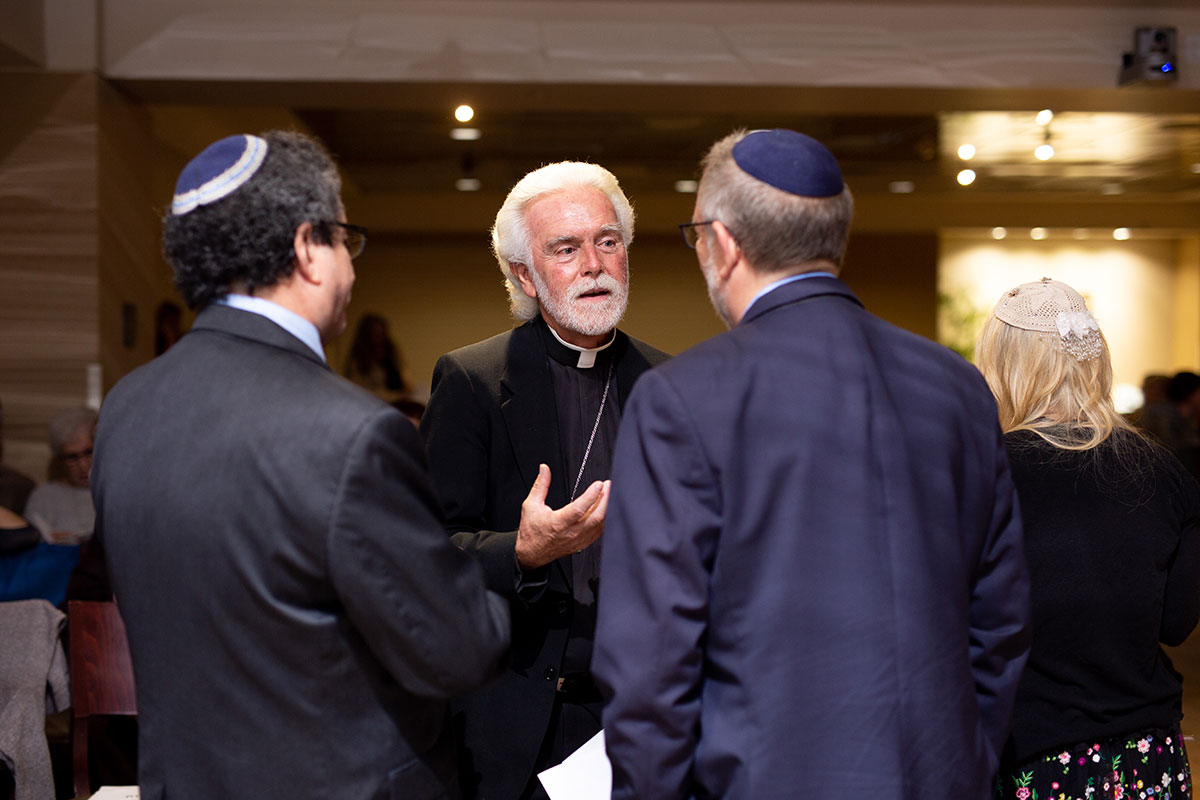 Two rabbis speaking with a priest