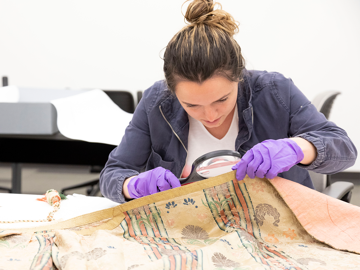 Student examining object with magnifying glass
