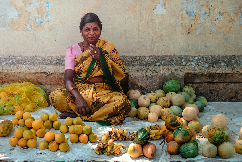 Photo of woman sitting on the floor surrounded by fruits and vegetables