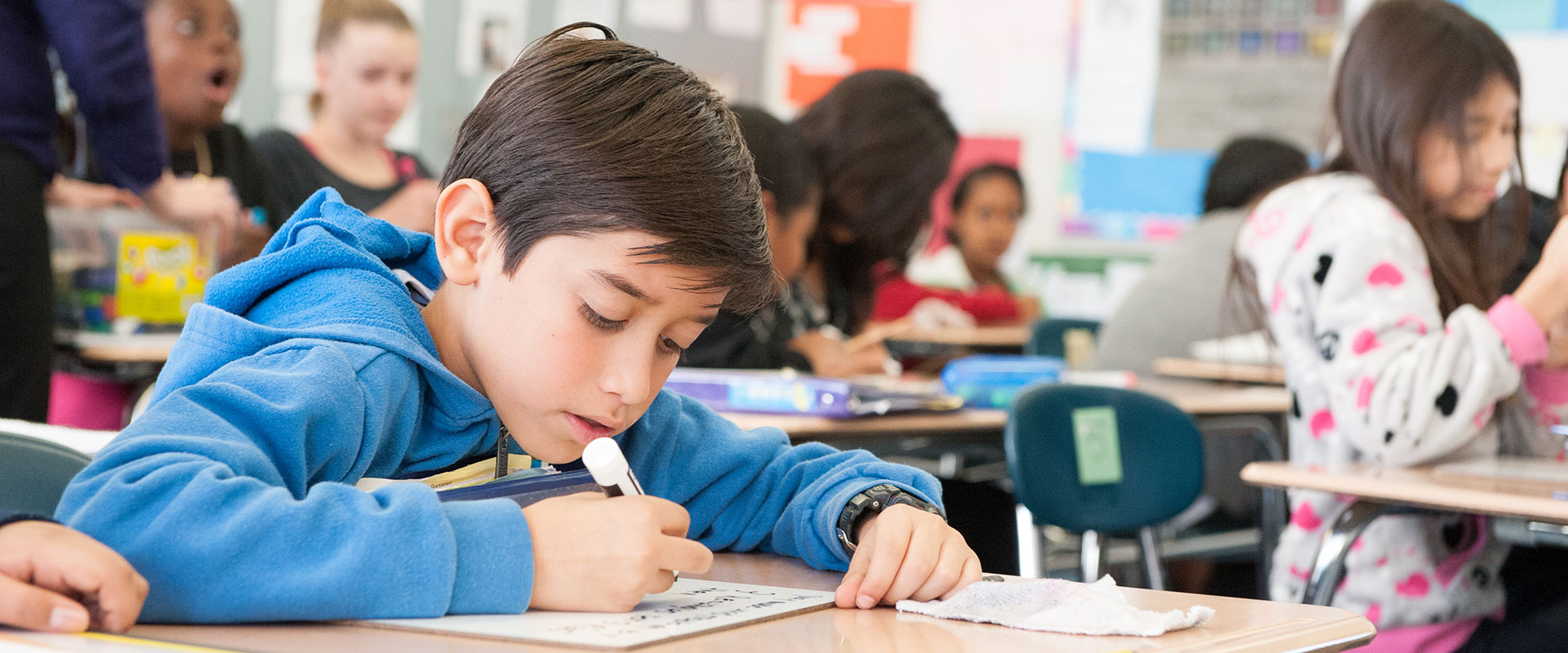 An elementary student writing on a white board